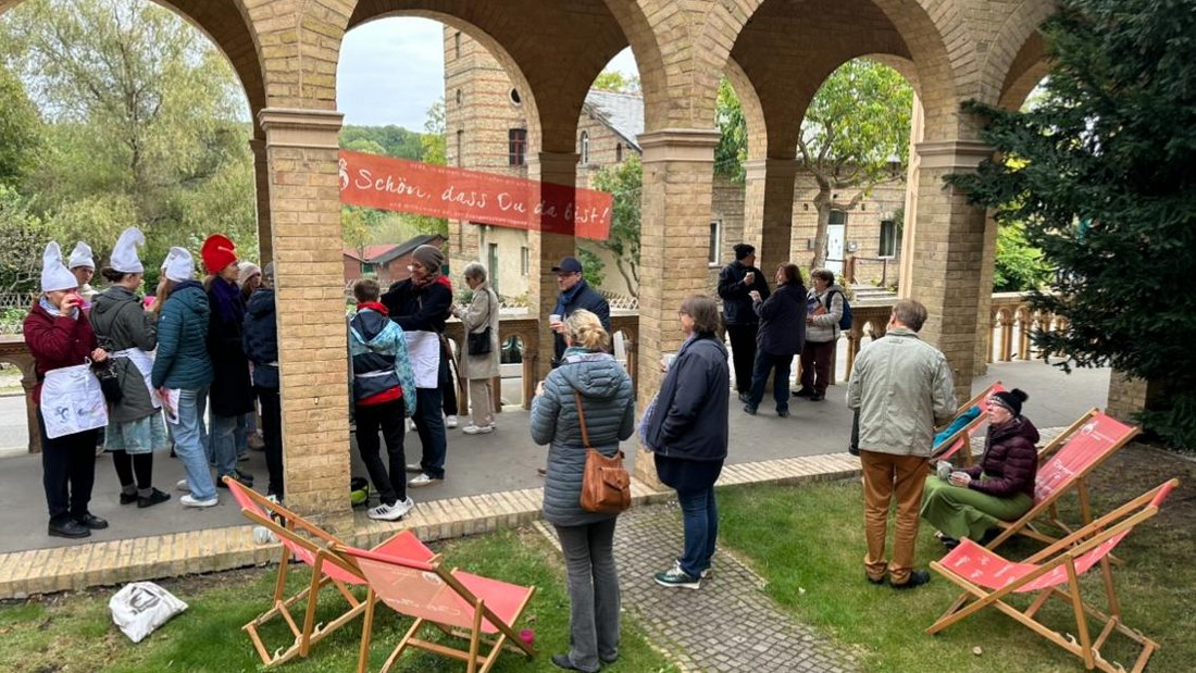 Menschen stehen unter den Arkarden der Evangelischen Kirche Potsdam-Bornstedt